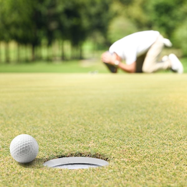 Man golfer feeling disappointed after a putted golf ball missed the hole